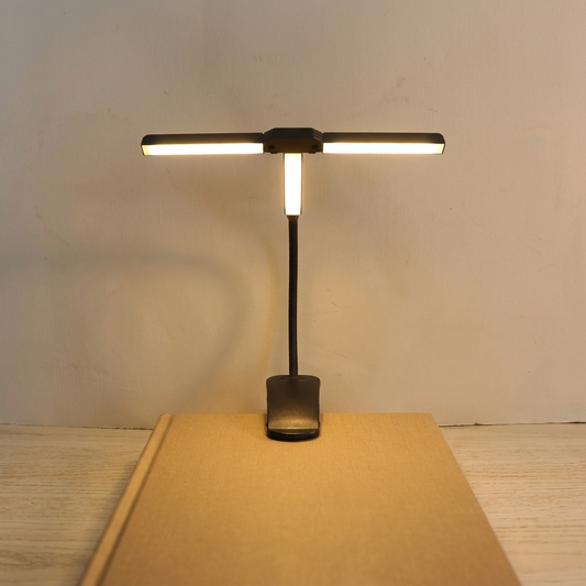Clip on book light, Button Switch, clipped to a hardcover book against a limewashed sand wall