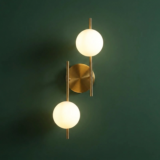 Double head glass globe wall sconce with two milky frosted shades on an offset arm, lit, on a deep green wall