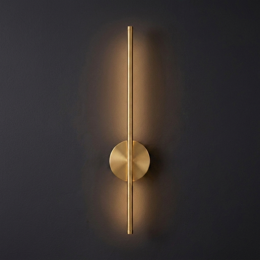 Single 20 inch magnetic linear wall sconce in brushed brass gold, lit, on a deep charcoal wall