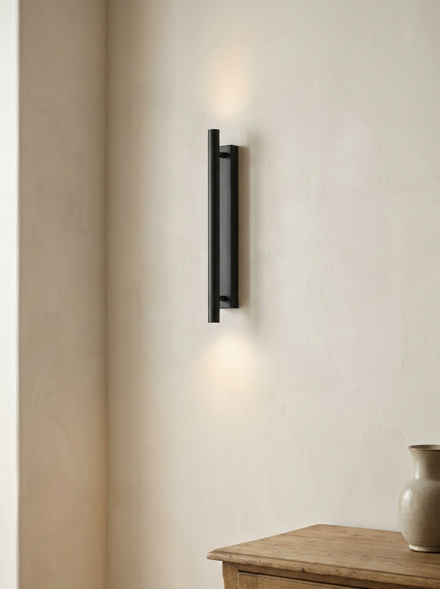 Matte black cordless wall sconce casting warm light on a plaster wall